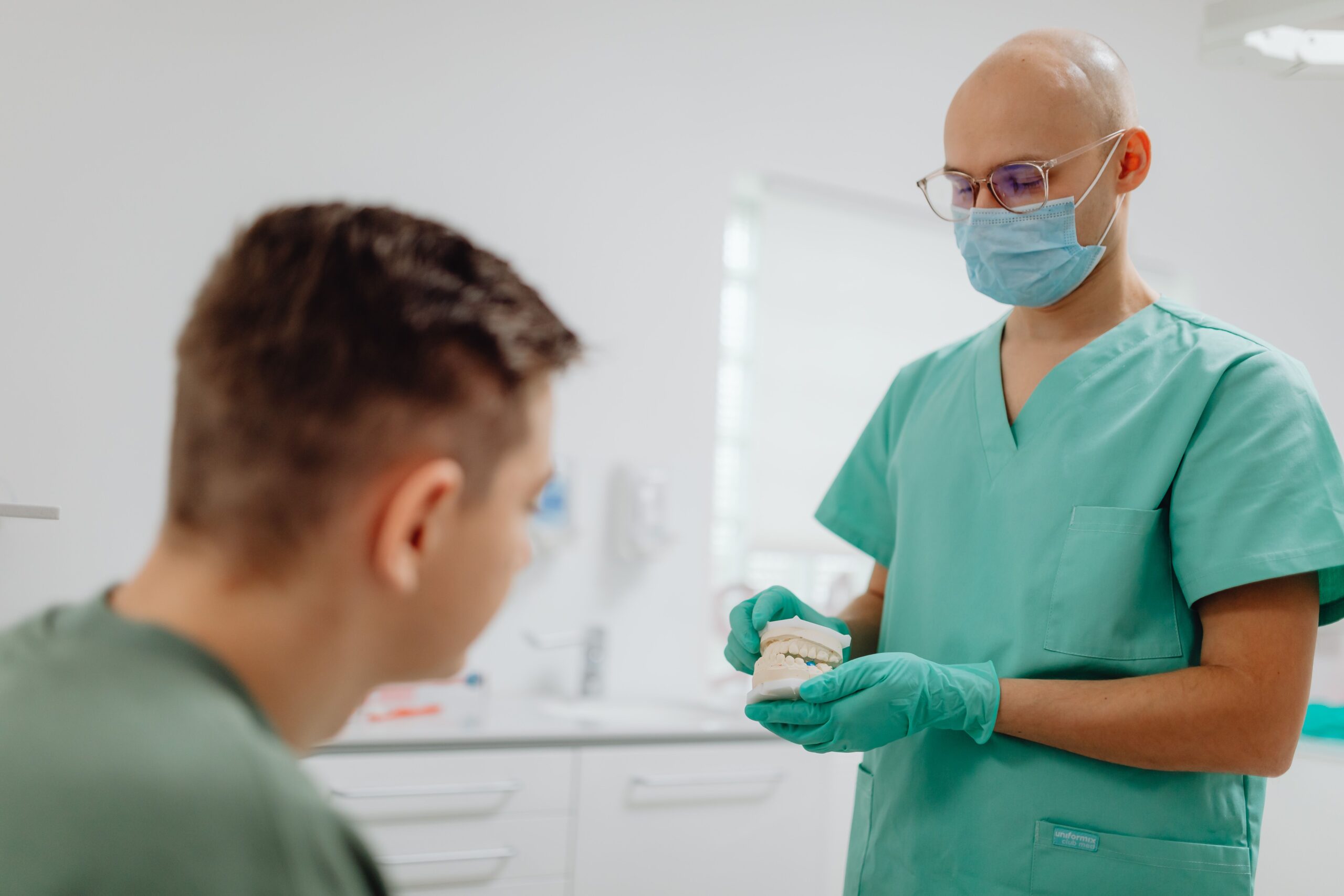 Dentist explaining a dental cyst treatment plan from an X-ray to a patient in Sri Petaling